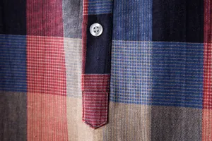 Close-up detail of a colorful plaid linen-like shirt with a white button