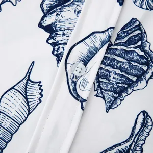 Detailed view of the blue seashell print and button on white men's beach shirt