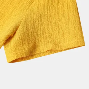 Macro view of yellow men's shirt showing the breathable crinkled fabric texture and hem