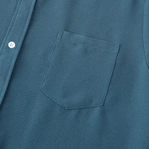 Close-up view of blue textured men's casual summer shirt showing pocket and button detail