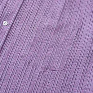 Primer plano de la tela acanalada de una camisa morada con bolsillo de pecho y botón blanco.