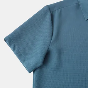 Close-up of blue textured fabric and sleeve detail on men's short sleeve shirt.