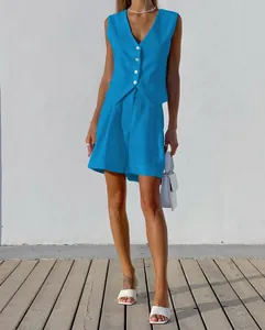 Stilvolles Model trägt ein hellblaues Weste-und-Shorts-Set aus Baumwollleinen vor weißer Wand
