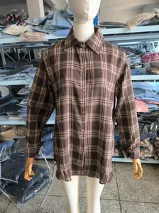 Dettaglio di una camicia a maniche lunghe a quadri marrone su un busto di manichino