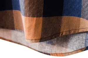 Macro view of the neat hem and textured plaid fabric of a men's casual shirt.