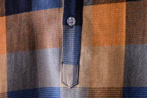 Macro shot of the button placket and fabric texture on a blue and orange plaid shirt