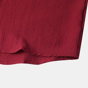 Detailed close-up showing the dark red textured fabric hem and neat stitching of a men's shirt