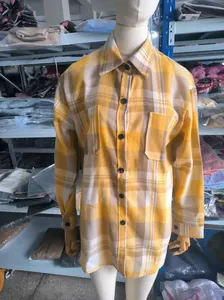 Close-up detail of yellow plaid long sleeve shacket with buttons and chest pockets