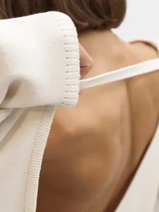 Détail d'un pull en maille crème avec dos nu sexy et texture en coton doux et confortable