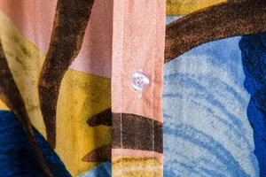 Macro detail showing high-quality stitching, transparent button, and vibrant floral fabric print