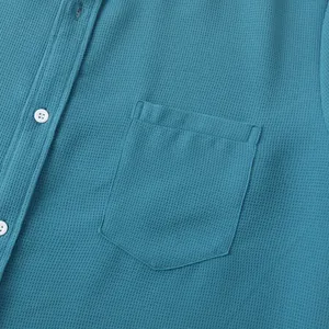 Macro view showing waffle texture fabric and chest pocket on blue casual shirt.