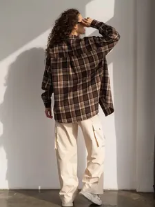 Achteraanzicht van een vrouw in een vintage bruin geruit overhemd en beige cargobroek