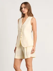 Ensemble élégant gilet et short en lin crème porté par un mannequin féminin en vue latérale.