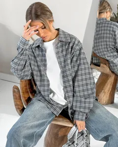 Lifestyle detail of woman wearing an oversized grey plaid shirt and jeans.