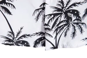 Primer plano de una camisa blanca para hombre con estampado de palmeras negras y costuras.