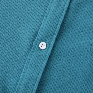 Close-up macro view showing blue waffle knit fabric texture and white button detail.