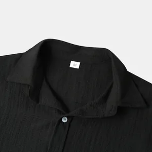 Close-up detail of a men's black textured short-sleeve shirt collar with size M label