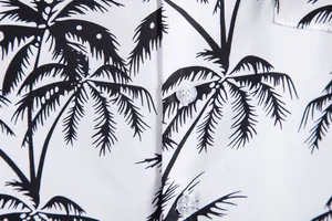 Detalle de una camisa casual para hombre con estampado de palmeras negras en tela blanca.
