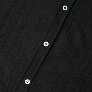 Close-up detail of textured fabric and white buttons on a black men's short sleeve shirt
