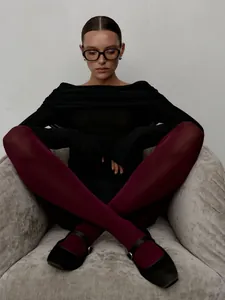 Detailed view of a black off-the-shoulder slim-fit knit top on a model in a chair.