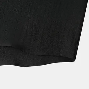 Detail of black men's short sleeve shirt hem showing fabric texture and sewing finish