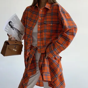 Vista dettagliata di una camicia a scacchi arancione oversize in stile collegiale.