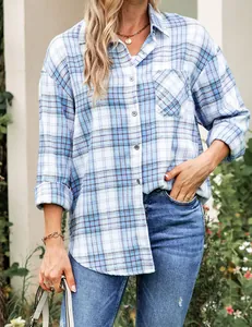 Detailed view of women's blue plaid button-down long-sleeved shirt in outdoor setting