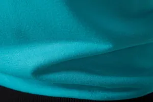 Gros plan détaillé sur la texture du tissu respirant de ce gilet de sport bleu sarcelle