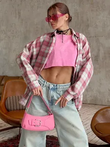 Model wearing a pink plaid oversized shirt over a pink crop top with a street style vibe