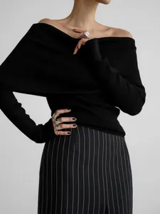 Close-up of elegant black off-the-shoulder knitted sweater for women in pinstripe skirt