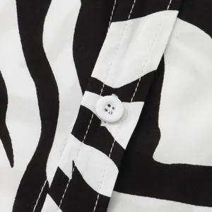 Detailed macro view of a zebra print shirt featuring white button and stitching.