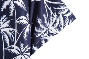 Detalle del puño de la camisa de hombre de manga corta con estampado de palmeras en azul marino.