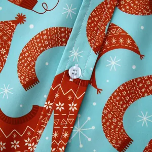 Détail macro d'une chemise hawaïenne bleu clair avec imprimé festif orange et bouton.