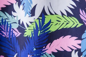 Macro view of vibrant tropical leaf print on Hawaiian short sleeve shirt fabric texture
