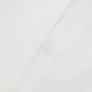 Macro detail of a white button and woven fabric texture on a men's casual shirt.