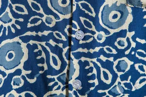 Detail view of ethnic floral print fabric and buttons on a blue Hawaiian casual shirt