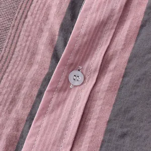 Close-up view of pink and charcoal striped linen fabric and button on men's shirt
