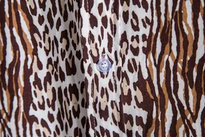 Macro view showing the leopard print fabric texture and clear button on a men's casual shirt