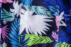 Close-up detail of a colorful tropical floral print Hawaiian shirt with pocket and buttons.