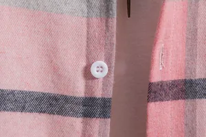 Dettaglio macro del bottone bianco e del tessuto a quadri rosa su camicia uomo