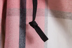 Dettaglio ravvicinato della coulisse nera su una camicia a quadri rosa e grigia con cappuccio