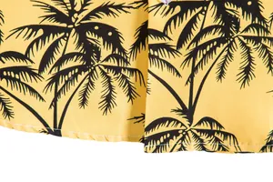 Detalle de cerca de camisa casual amarilla para hombre con estampado de palmeras.