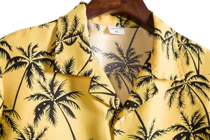Detalle del cuello de una camisa casual amarilla con estampado de palmeras negras.