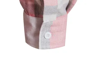 Dettaglio ravvicinato di un polsino di camicia a quadri rosa e bianco con bottone bianco