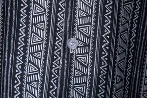 Macro detail showing ethnic tribal print pattern and button on a black and white shirt
