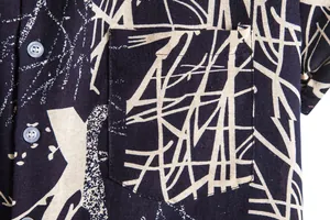 Close-up of men's Hawaiian shirt fabric showing detailed print and breast pocket.