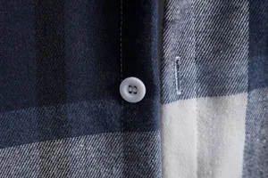 Dettaglio ravvicinato di camicia a quadri blu scuro con bottone e trama fine del tessuto
