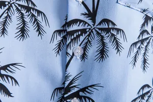 Detalle macro de camisa casual azul para hombre con estampado de palmeras y botón