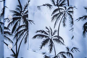 Detalle del bolsillo y estampado de palmeras tropicales en camisa azul de hombre