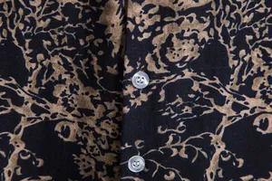 Macro detail of vintage gold floral print fabric and translucent buttons on men's shirt